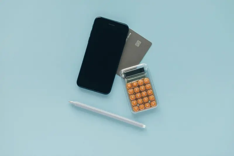 Phone, bank card and pocket calculator on a blue desk