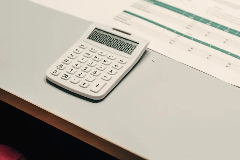 White calculator on a printed payroll spreadsheet