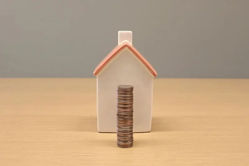 Stacked coins in front of a porcelain model house