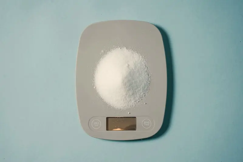 Digital kitchen scale weighing a heap of sugar
