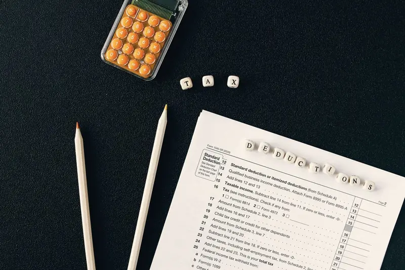 Tax forms, pencils and a calculator on a dark desk